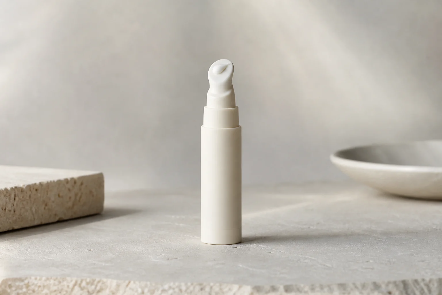 Representative eye-area care product image with a small unlabelled pump tube and a minimal amount of white cream